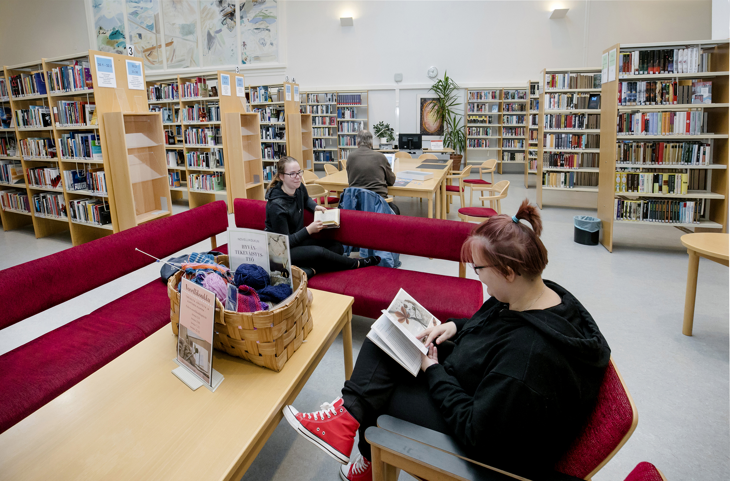 Henna Laakso (vas.) ja Emmi Pitkäkari lueskelevat Kemin kaupunginkirjastossa, sohvilla.