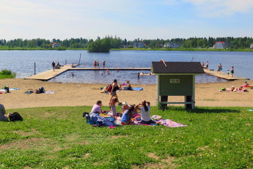 Uimaranta ja laitureita, paljon ihmisiä rannalla.